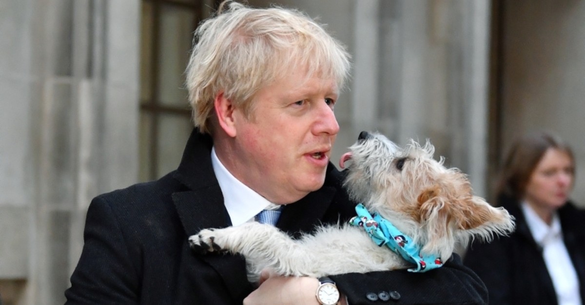 Britain's Prime Minister Boris Johnson holds his dog Dilyn as leaves a polling station, at the Methodist Central Hall, after voting in the general election in London, Britain, December 12, 2019. (Reuters Photo)