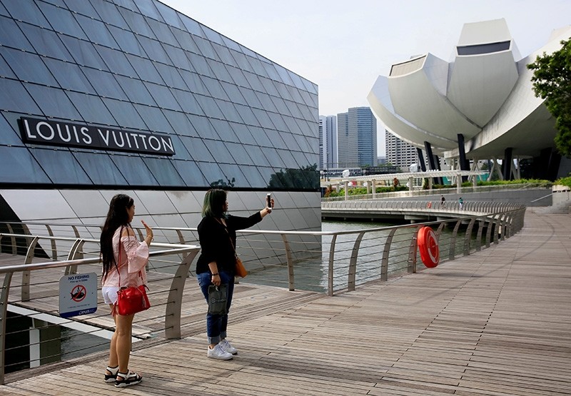 Shoppers take selfies in front of a Louis Vuitton shop in Singapore May 19, 2017. (Reuters Photo)