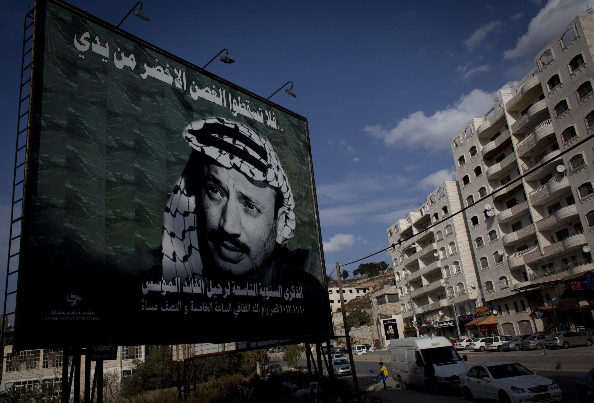 A youth plays soccer by a big poster of late Palestinian leader Yasser Arafat in the West Bank city of Ramallah, Friday, Nov. 8, 2013. (AP Photo)