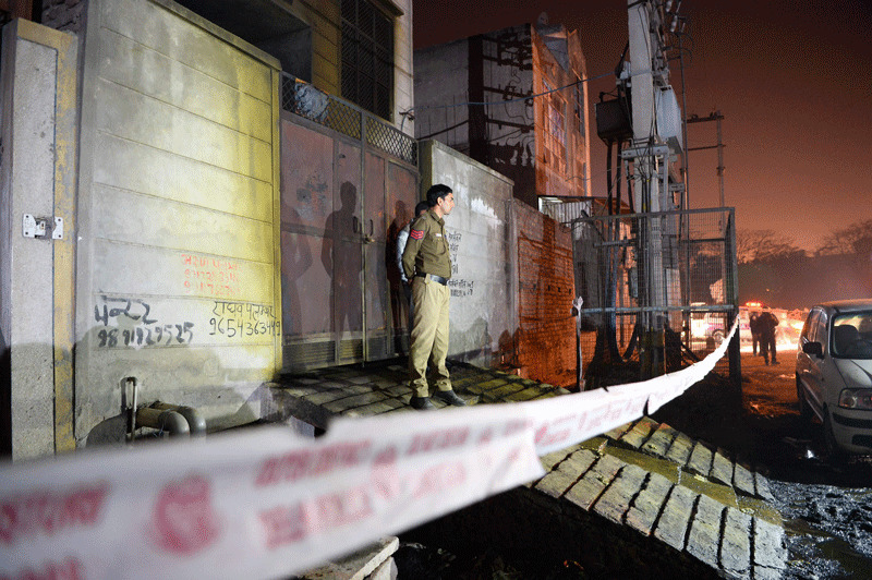 Police stand guard in front of a plastic factory in the Bawana industrial area on the northern edge of New Delhi on January 20, 2018 after a fire killed at least 17 workers. (AFP Photo)