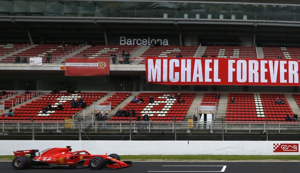 Ferrari driver Sebastian Vettel of Germany drives by a tribute-banner in honor of former German driver Michael Schumacher during a Formula One pre-season testing session in Barcelona.