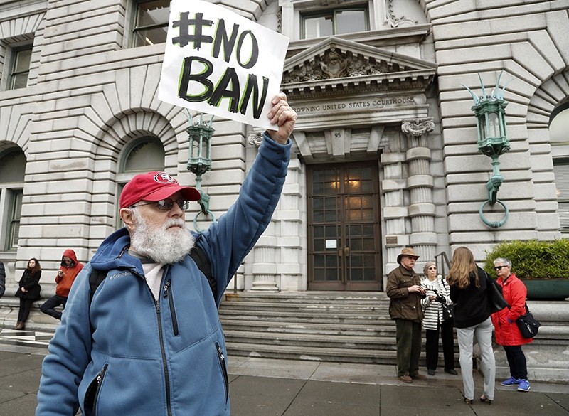An anti-travel ban protestor with a poster reading 'NO BAN' stands outside the Ninth US Circuit Court of Appeals (EPA Photo)