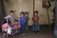 Syrian children stand outside of a tent in Idlib.