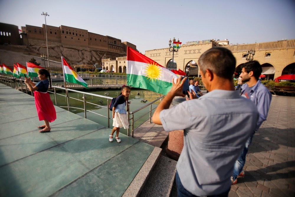 A man takes a picture of his daugther near the Kurdistan flag at the castle of Irbil, northern Iraq, July 29, 2017. 