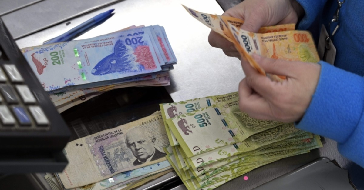 In this file photo taken on August 15, 2019 a cashier counts Argentine pesos bills at a supermarket in Buenos Aires. (AFP Photo)