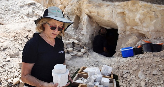 Yardena Alexander, an Israeli archeologist, inspects chalkstone cores and mugs uncovered two-months prior at an excavation site dating to the Roman period in the Israeli village of Reina (AFP Photo)