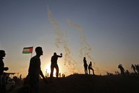 Palestinians protest as tear gas fumes erupt near the border with Israel in the southern Gaza Strip on May 15, marking 70th anniversary of Nakba.