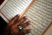 An elderly man touches pages of the Quran as he reads it after noon prayers on the second day of the Muslim holy month of Ramadan in Amman.