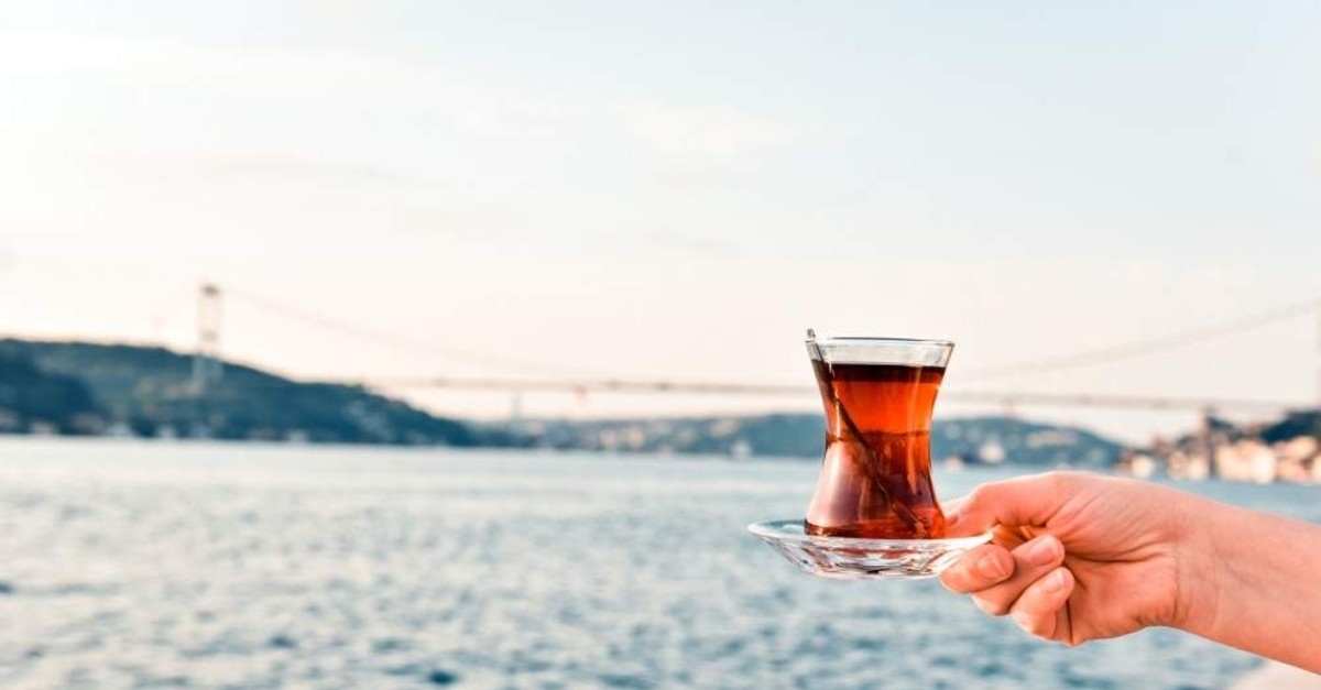 A woman holds a glass of black tea at the Bosporus, Istanbul. (iStock)