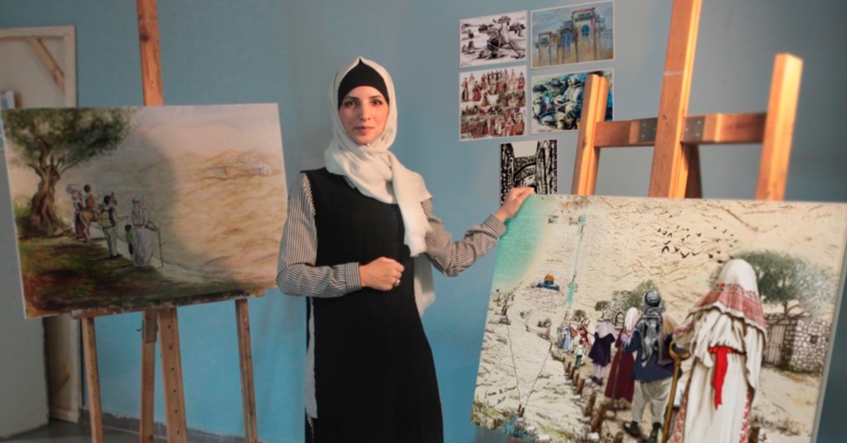 Palestinian artist Iman Abu Arra poses with her paintings in her studio at Hacettepe University in Ankara.