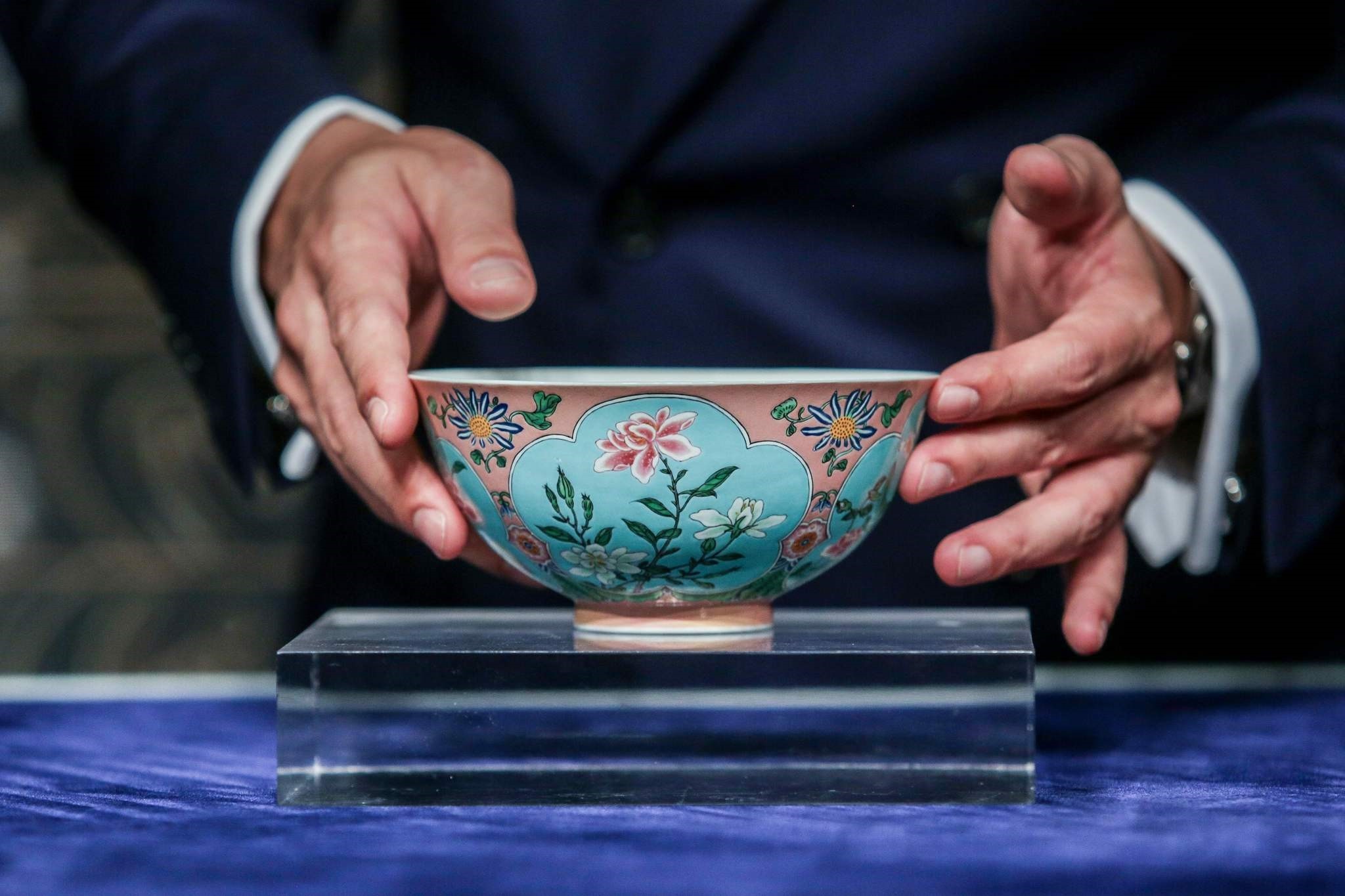 Nicolas Chow, deputy chairman for Sotheby's Asia, holds an extremely rare Qing Dynasty bowl -- one of only three known to exist -- during a media preview at Sotheby's in Hong Kong on April 3, 2018 (AFP Photo)