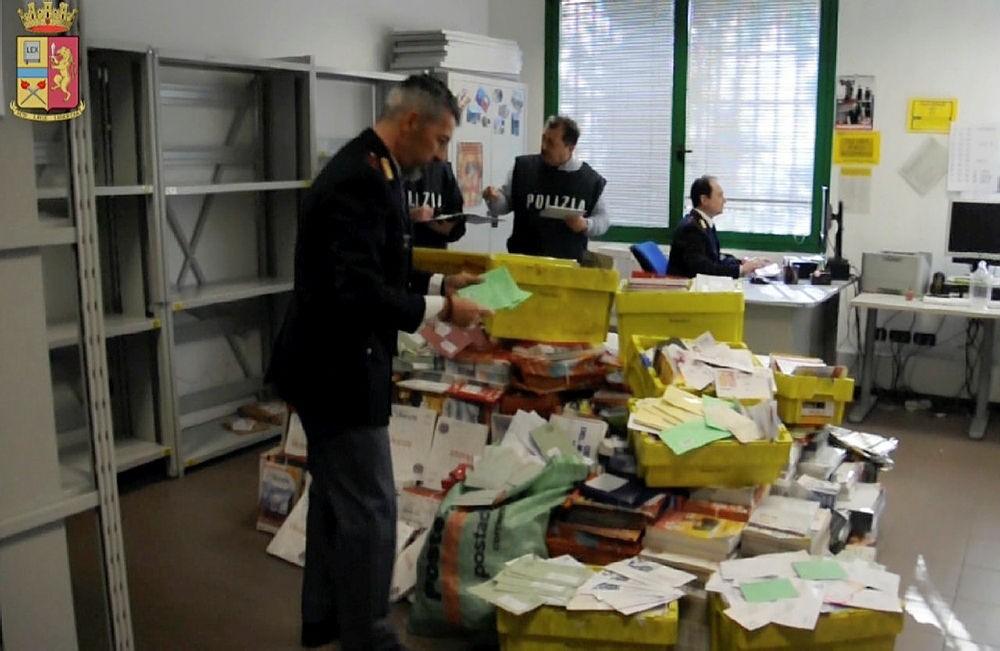This frame made from a video by the Italian police made available Jan. 31, 2018 shows postal police officers sorting out undelivered mail found in a postman's garage, in Vicenza, northern Italy. (AP Photo)