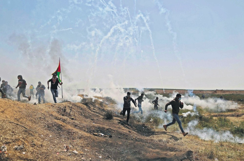 Palestinians run for cover from tears gas at the Israel-Gaza border, Gaza Strip, April 6.