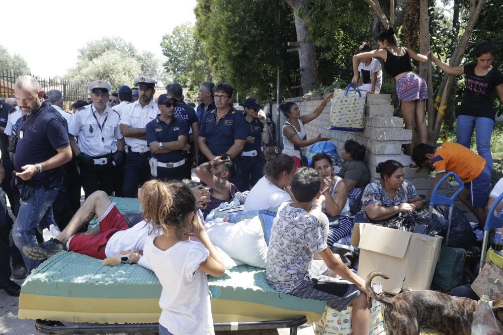 Italian police stand by evicted Roma people and their belongings outside the Camping River village, Rome, July 26.