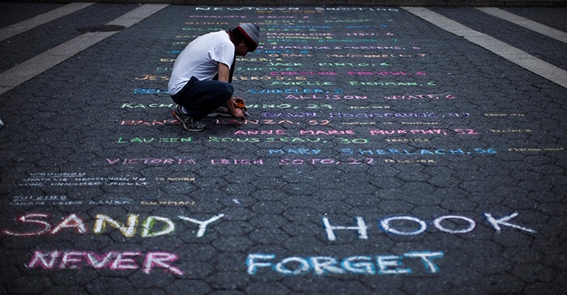 Street artist Mark Panzarino, 41, prepares a memorial as he writes the names of the Sandy Hook Elementary School victims during the six-month anniversary of the massacre (Reuters File Photo)