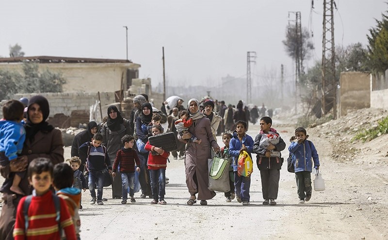 Syrians civilians evacuated from the eastern Ghouta enclave pass with belongings through the regime-controlled corridor opened by government forces in Hawsh al-Ashaari, east of the enclave town of Hamouria on March 15, 2018. (AFP Photo)