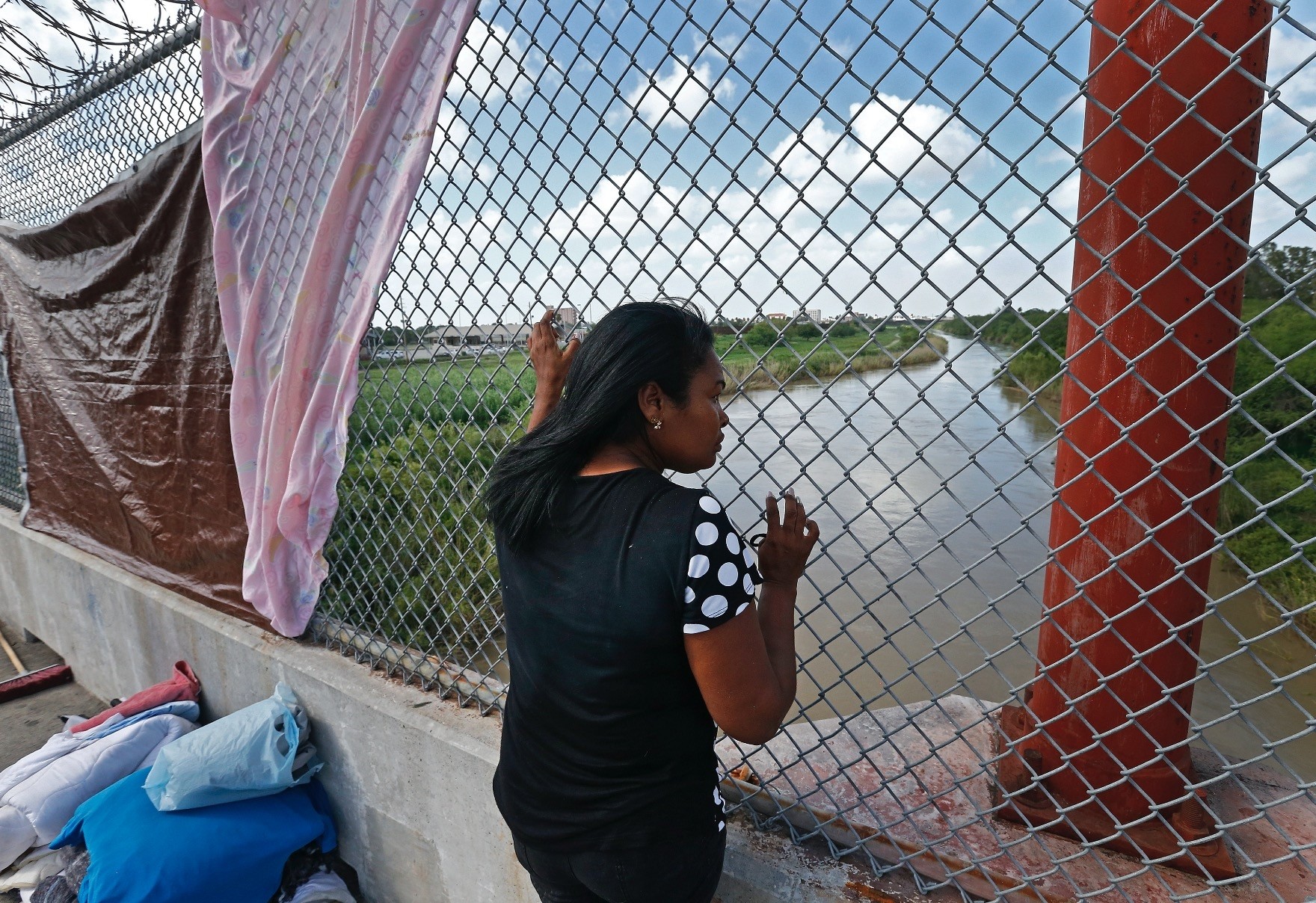 An immigrant from Cuba seeking asylum looks out across the Rio Grande River while waiting on the middle of a bridge to get into the United States from Matamoros, Mexico.