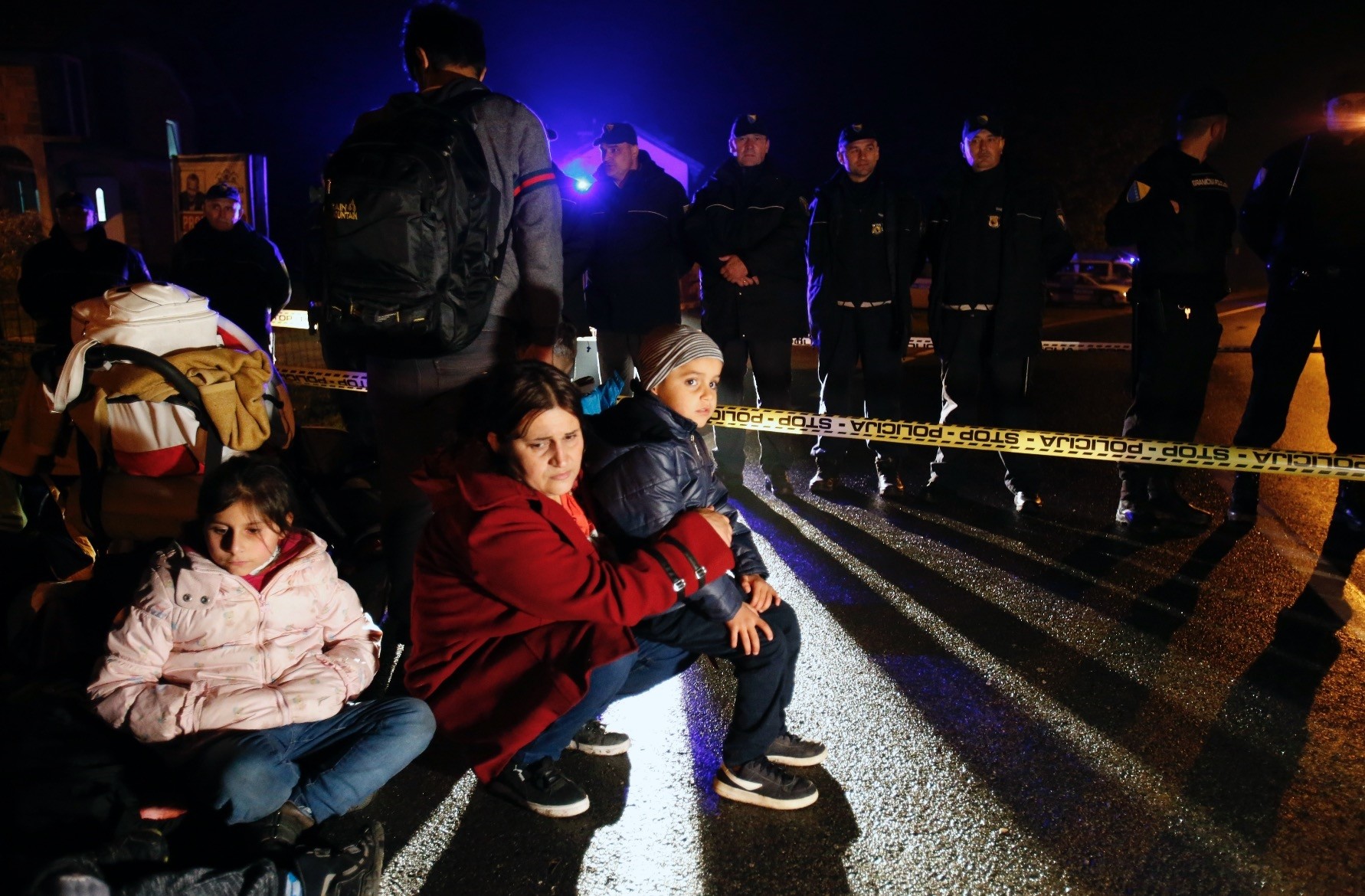 A migrant woman holds her child near a police barricade at the border crossing of Izacici, Bosnia, Oct. 22.
