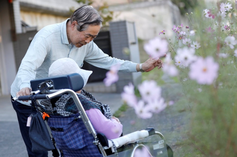 Eiichi Okubo (top), 71, speaks to his wife Yumiko, 68, who suffers from dementia, near her care house in Tokyo, Japan, Oct. 29.