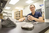 Erik Gulbranson, paleoecologist and visiting assistant professor at UWM, studies some of the fossilized trees he brought back from Antarctica. (UWM Photo/Troye Fox)