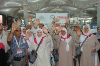 Pilgrims wave before they board an airplane to Saudi Arabia, July 5, 2019.