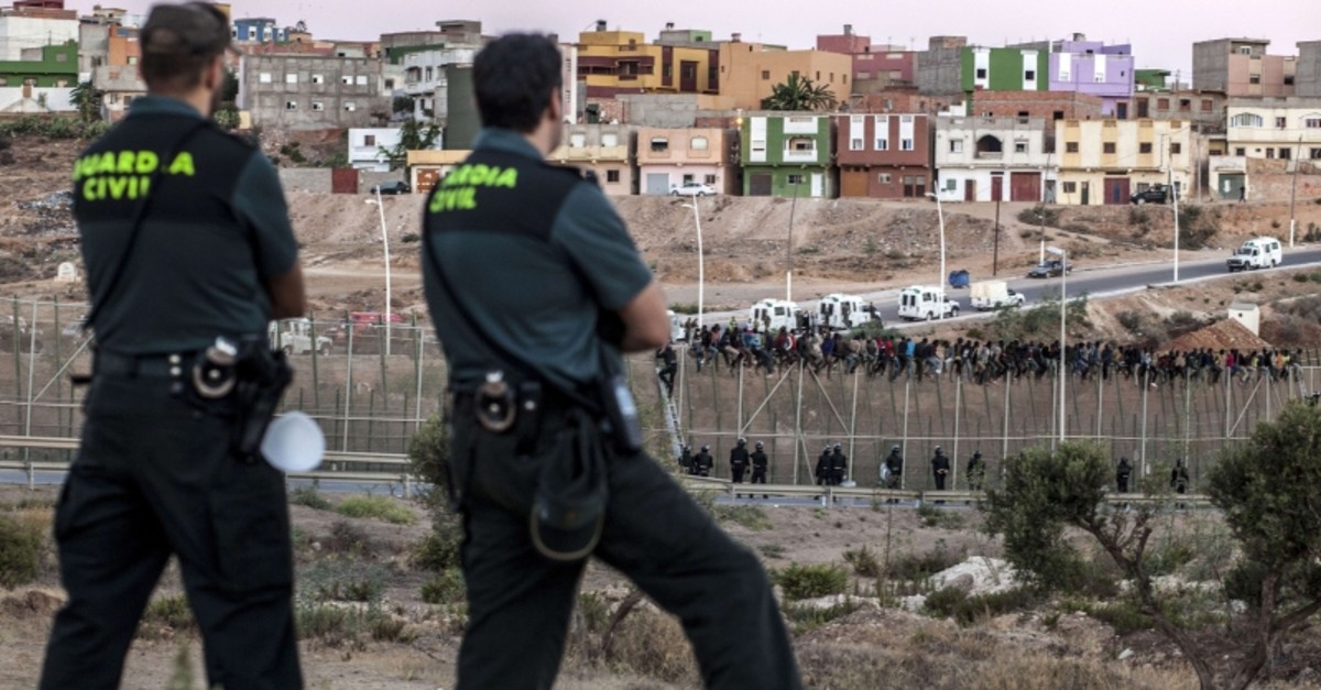 This Aug. 13, 2014, file photo shows Spanish Guardia Civil watching as would be immigrants from Africa sit atop a metallic fence that divides Morocco and the Spanish enclave of Melilla. (AFP Photo)