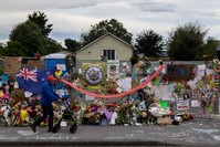 A man walks past flowers and tributes displayed in memory of the twin mosque massacre victims along the road outside the Linwood mosque (back C) in Christchurch, March 25, 2019. 