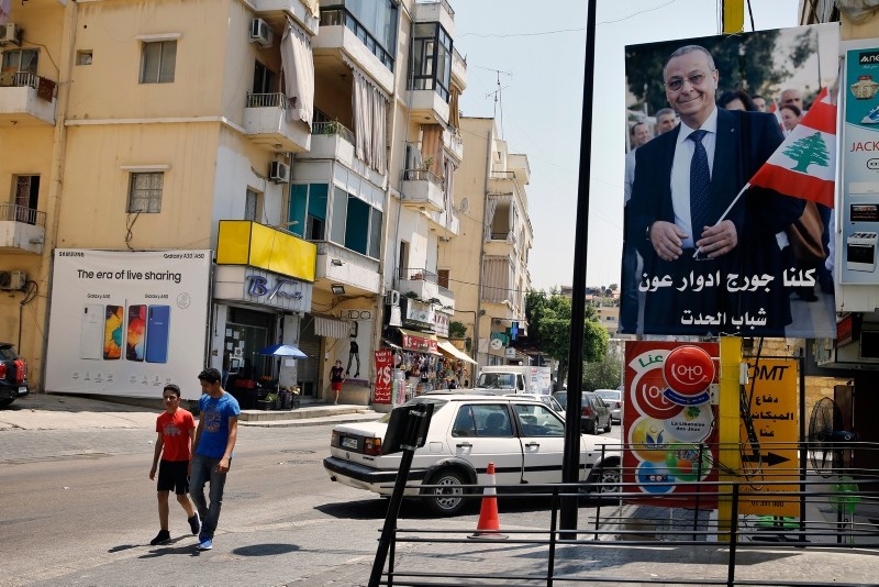 In this Monday, June 24, 2019 photo, a poster shows George Aoun, head of the municipality of the village of Hadat, with Arabic that reads ʺWe are all George Edward Aoun. |(AP Photo)