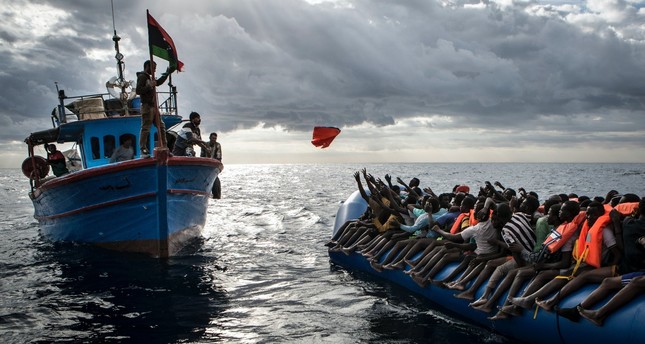 Libyan fishermen throw a life jacket at a rubber boat full of migrants trying to reach Italy soils, Feb. 13, 2017.