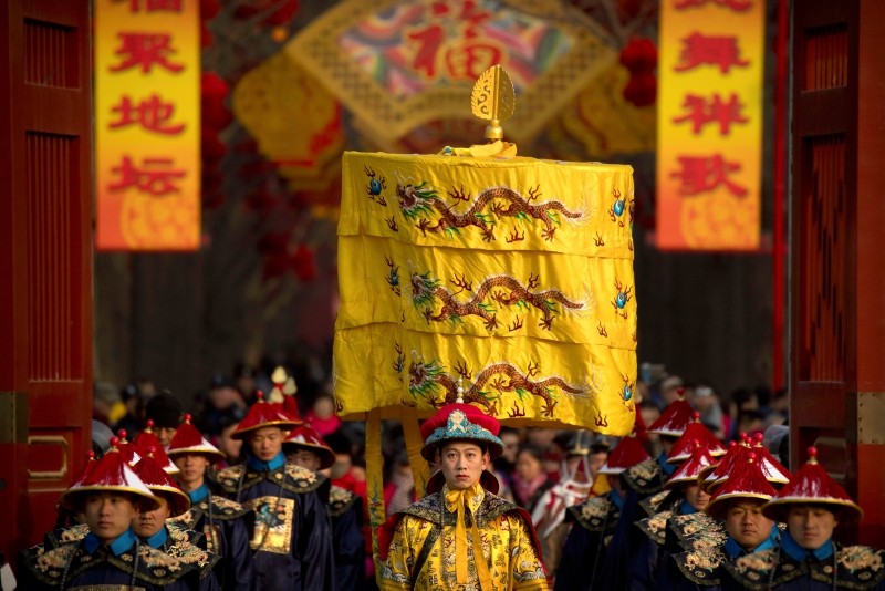 A performer dressed as an emperor, center, participates in a Qing Dynasty ceremony in which emperors prayed for good harvest and fortune at a temple fair in Ditan Park in Beijing, Tuesday, Feb. 5, 2019. (AP Photo)