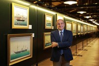 Erdem Cever poses in front of the works at the exhibition. 