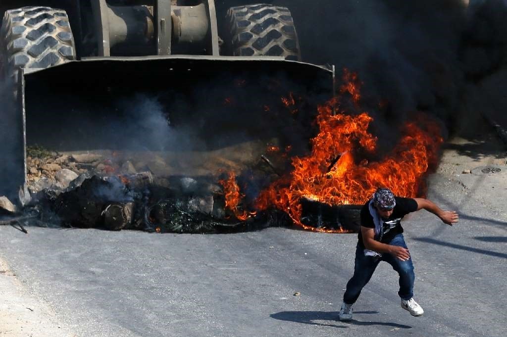 A Palestinian runs from the path of an Israeli army bulldozer during clashes in the village of Kobar, west of Ramallah, on July 22.