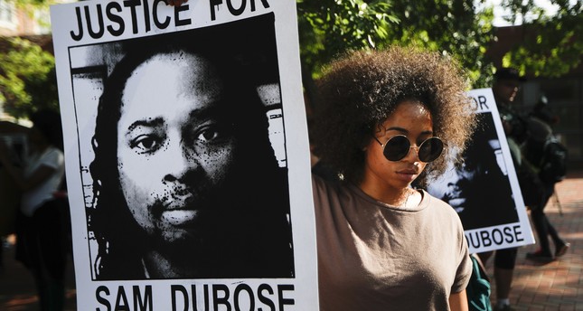 Protesters holds signs as they demand that a white former police officer be tried a third time in the fatal shooting of an unarmed black motorist, June 28, 2017. (AP Photo)