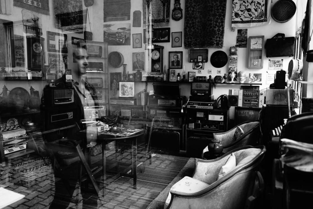 A man looks in through the window of an antique shop.