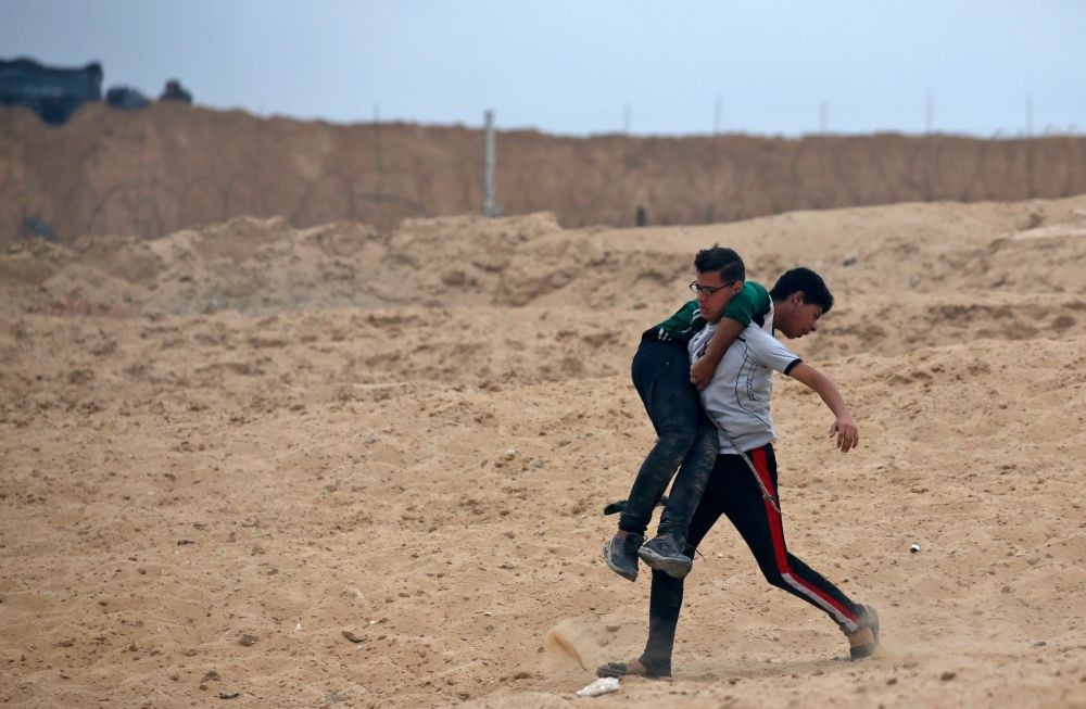 A Palestinian protestor carries a young boy who was injured during a demonstration on a beach near the maritime border with Israel in the northern Gaza Strip, Oct. 1.