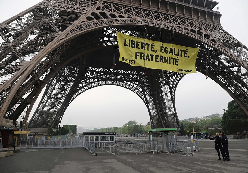 Police officers stand by after Greenpeace activists unveiled a banner reading ,liberty, equality, fraternity, on Eiffel Tower in Paris early on May 5, 2017. (AFP Photo)
