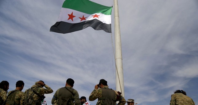 Syrian National Army troops raising the Syrian flag in Tal Abyad after the city's liberation from YPG terrorists (AA Photo)