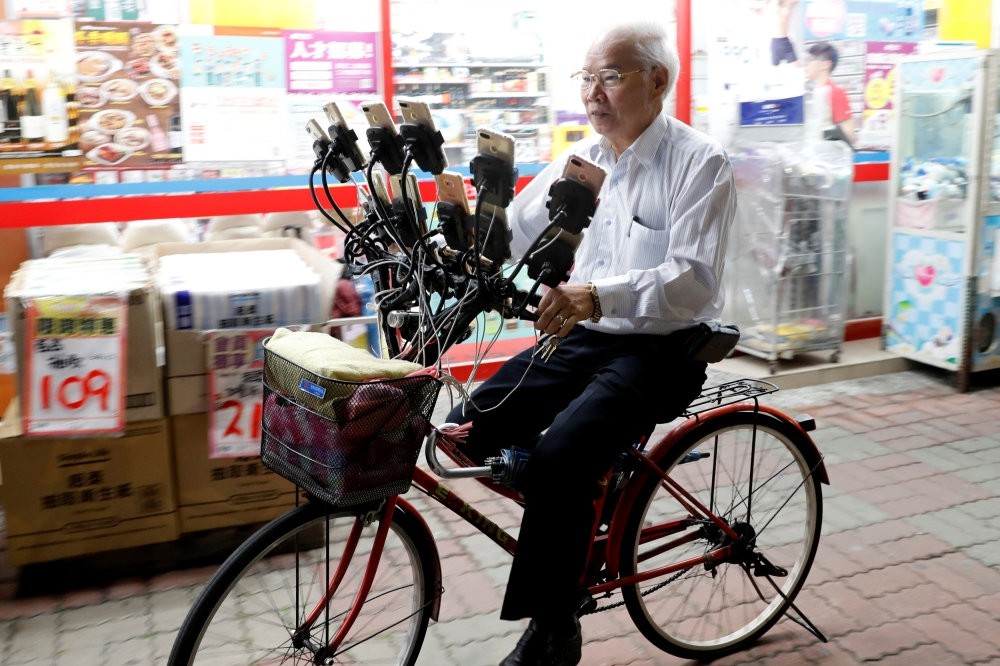 Taiwanese Chen San-yuan, 70, known as ,Pokemon grandpa,, rides his bicycle while playing ,Pokemon Go, on 15 mobile phones, New Taipei City, Taiwan, Nov. 12.
