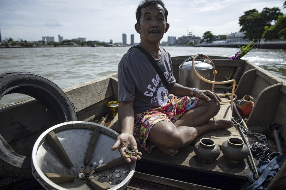Bhoomin Samang holding rare coins he found during previous diving trips to the bottom of the Bangkok's Chao Phraya river.