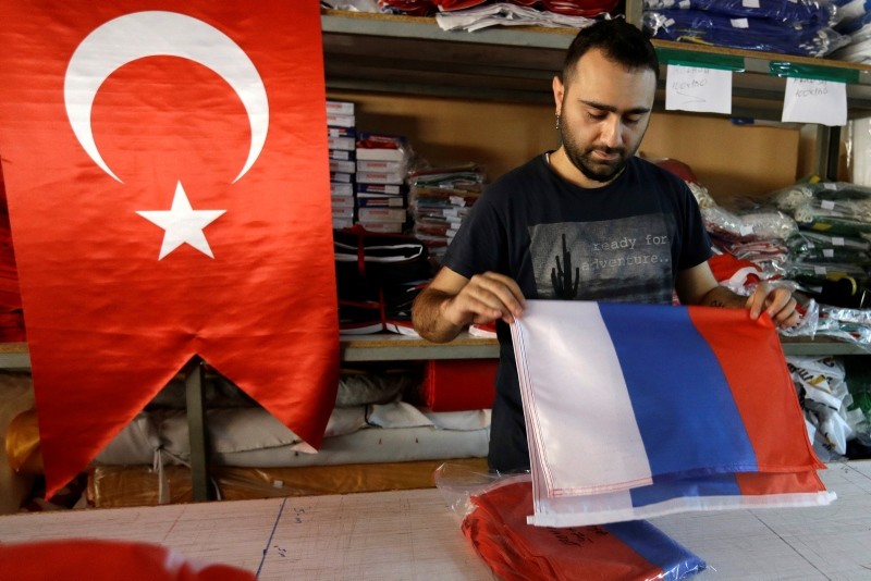 An employee of a flag-making factory folds a Russian flag as a Turkish flag adorns the display at left, in Istanbul, Tuesday, Aug. 9, 2016. (AP Photo)