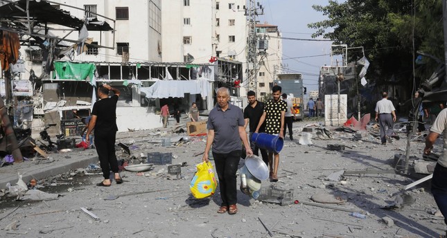 مدنيون يسيرون وسط مباني سكنية مدمرة جراء القصف الإسرائيلي على قطاع غزة صورة: الأناضول