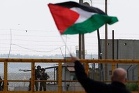 A Palestinian protester waves his national flag in front of Israeli security forces outside the compound of the Israeli-run Ofer prison in the Israeli occupied West Bank, March 30, 2016. (AFP Photo)