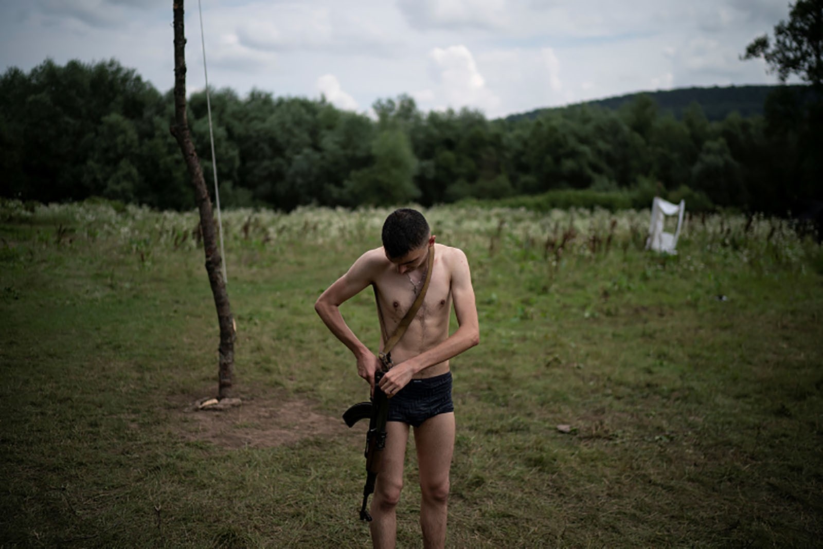 Mykhailo adjusts his AK-47 rifle after bathing in a river.