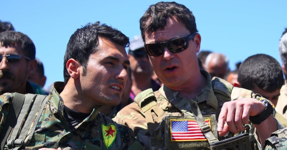 This file photo taken on April 25, 2017 shows a US officer, from the US-led coalition, speaking with a YPG terrorist at the site of Turkish airstrikes near northeastern Syrian Kurdish town of Derik, known as al-Malikiyah in Arabic, on April 25, 2017.