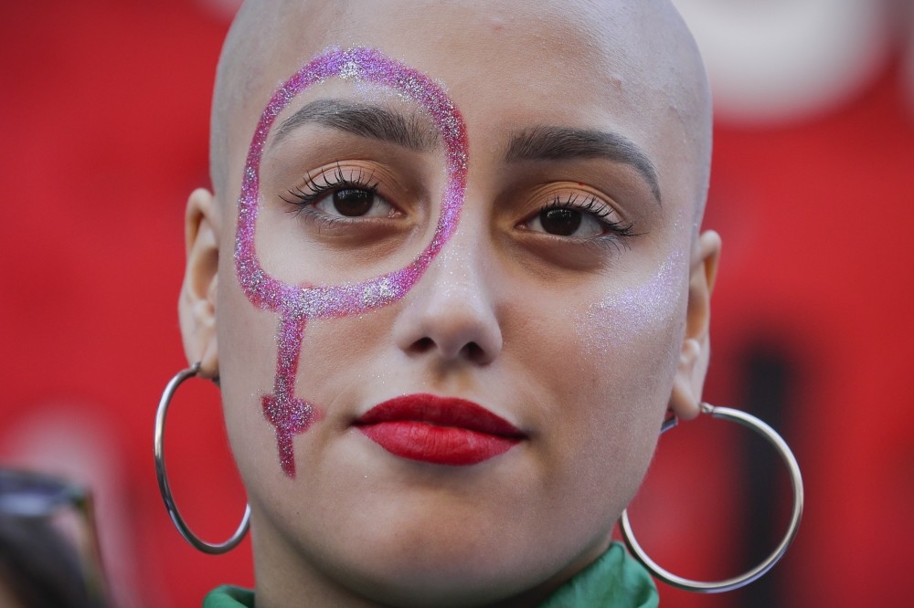 A woman with a Venus symbol painted on her face at a rally in Argentina.