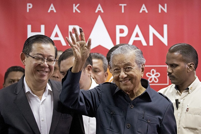 Malaysia's Prime Minister Mahathir Mohamad, center, waves next to newly appointed Finance Minister Lim Guan Eng, left, after a press conference to announce his cabinet members in Petaling Jaya, Malaysia, Saturday, May 12, 2018. (AP Photo)