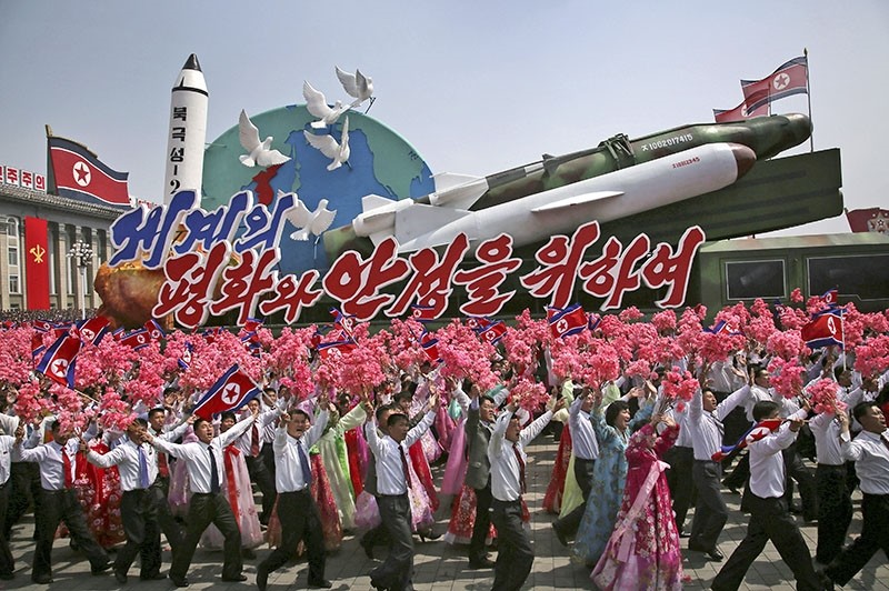In this April 15, 2017, file photo, people wave flags and plastic flowers as a float with model missiles and rockets with the words ,For Peace and Stability in the World, is paraded across Kim Il Sung Square in Pyongyang, North Korea. (AP Photo)
