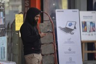 A Kashmiri man browses the internet on his mobile phone outside a shop, Srinagar, Jan. 30, 2020. (AP Photo)