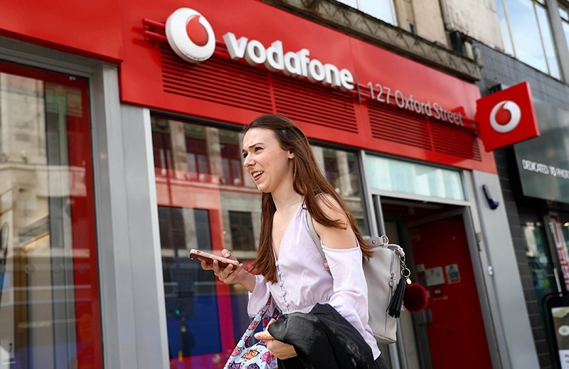 A woman holds a phone as she passes a Vodafone store in London, Britain May 16, 2017. (Reuters Photo)