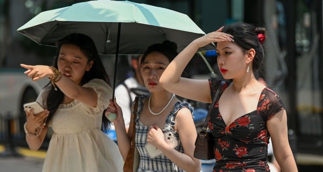 نساء في أحد شوارع شنغهاي التي تشهد طقسا حارا استثنائيا. 29 مايو 2023 الفرنسية